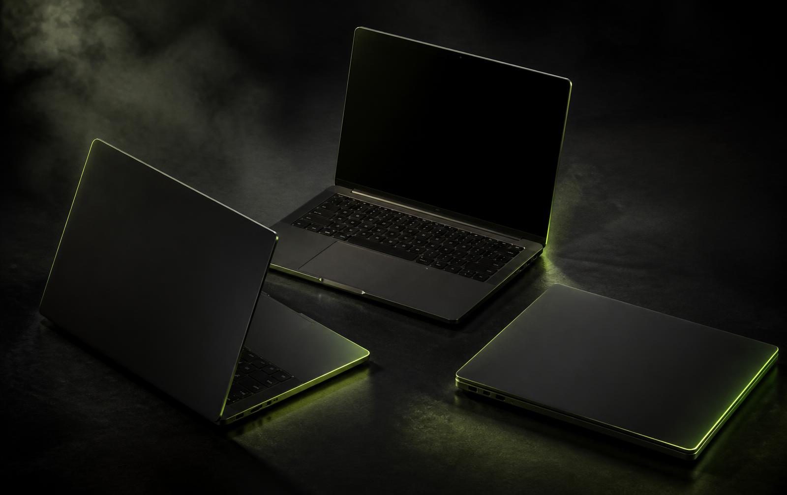 Tiga laptop bisnis modern dengan pencahayaan hijau lime di atas permukaan gelap